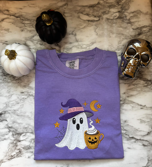 Comfort Colors T-Shirt in the color Violet with an embroidered ghost with a cute witch hat and a Halloween themed cup of coffee surrounded by stars and the moon.