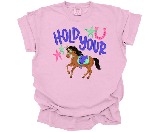 Comfort Colors T-shirt in the color Blossom with a colorful graphic design that has the words: "Hold Your", with a cute horse for the saying "Hold Your Horses".