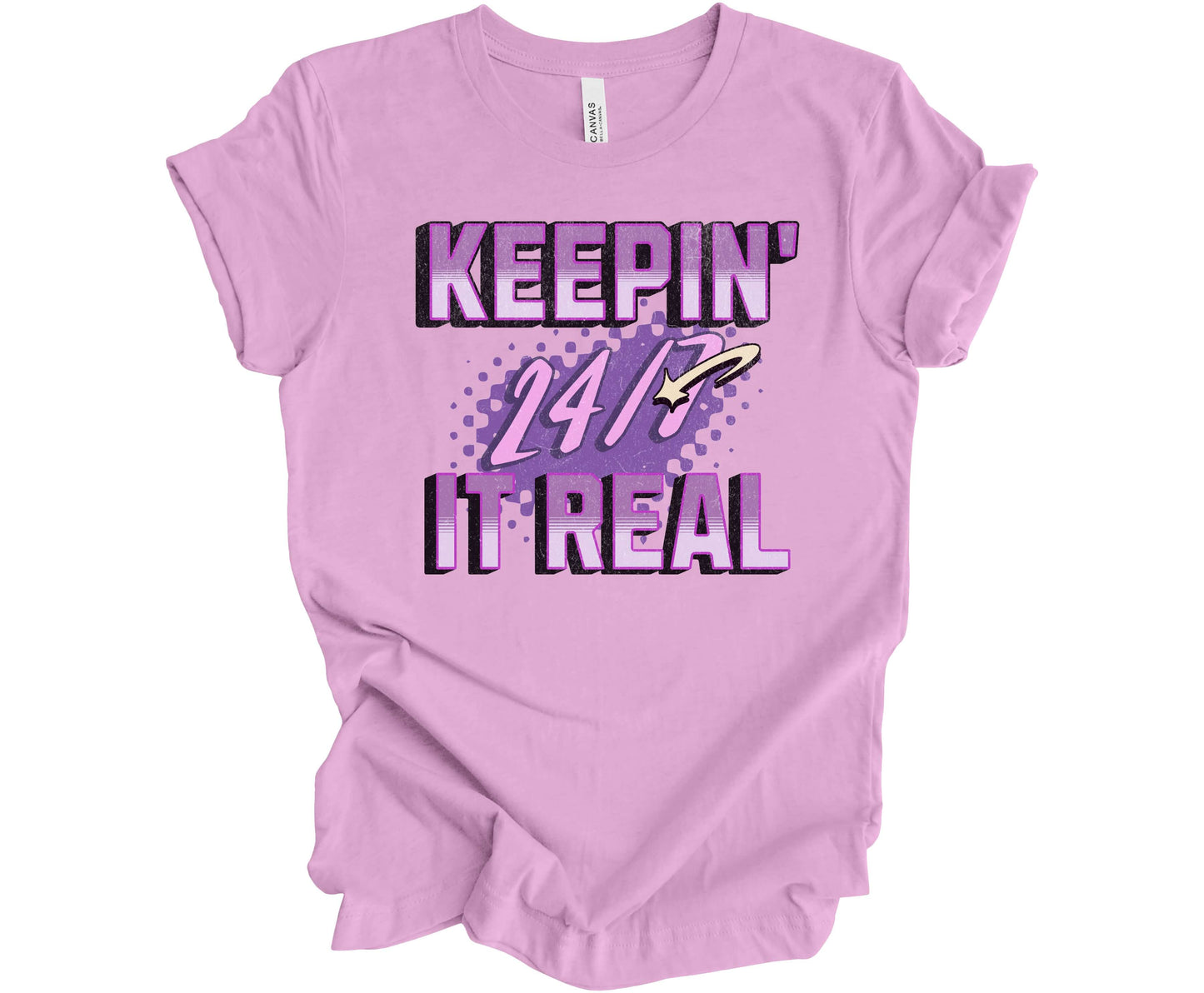 Bella Canvas T-shirt in Lilac with the words Keepin' It Real 24/7 in different shades of purple with a 3D effect