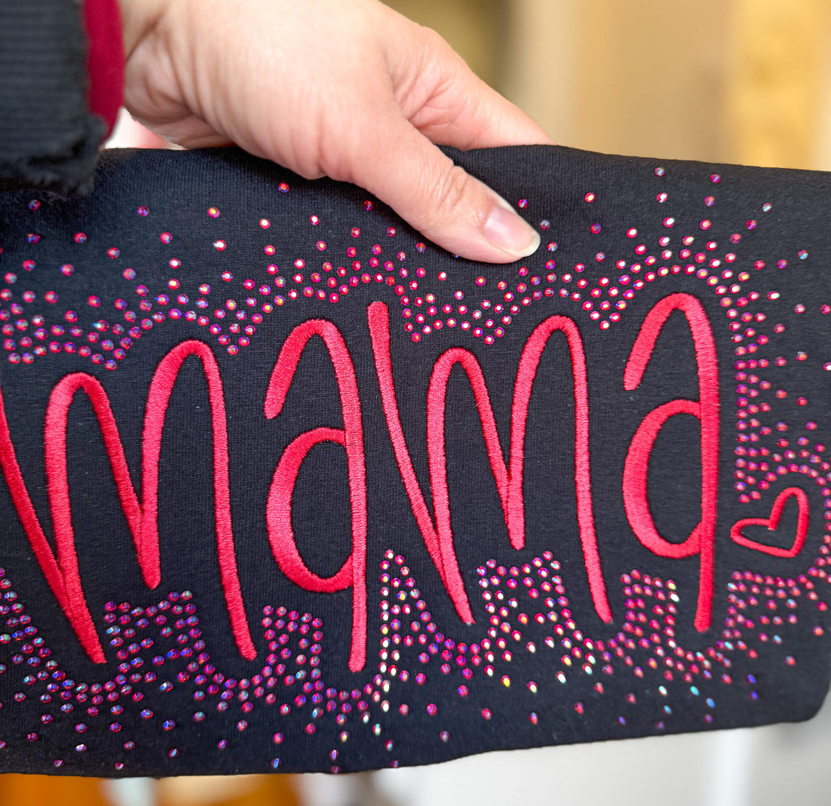 Listing is for Gildan Softstyle Sweatshirt with the word "MAMA" embroidered in a large font.  The sweatshirt colors offered are:  1) Ash Gray with hot pink stitching, 2) Black with red stitching, 3) Lt Pink with pink stitching and 4) Navy with medium blue stitching.  Each shirt comes with the option of adding a rhinestone splatter around the embroidery in a complimentary color.