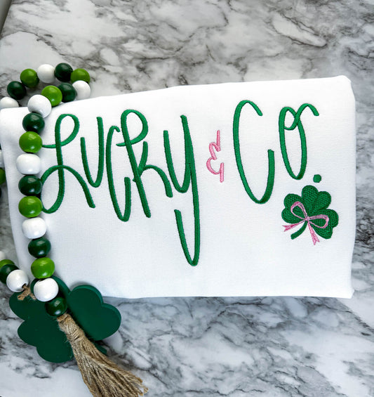 White Gildan Softstyle Sweatshirt with an embroidered design that says "Lucky & Co." with a cute shamrock and bow accent.  The wording is all in the color green, except for the "&" and the bow, which are in pink.  Very cute shirt for St.Patrick's Day festivities.