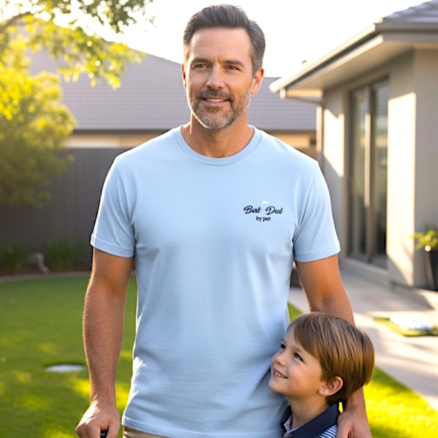 Male model wearing a Gildan Light Blue T-Shirt with a left chest embroidered design that says: "Best Dad by Par" with a golf flag.