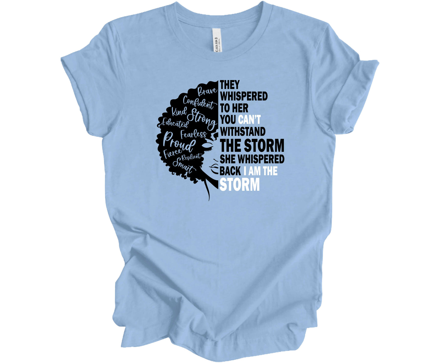 Bella Canvas T-shirt in Baby Blue with the silhouette of a woman's face with the powerful message "They whispered to her you can't withstand the storm she whispered back I am The Storm"