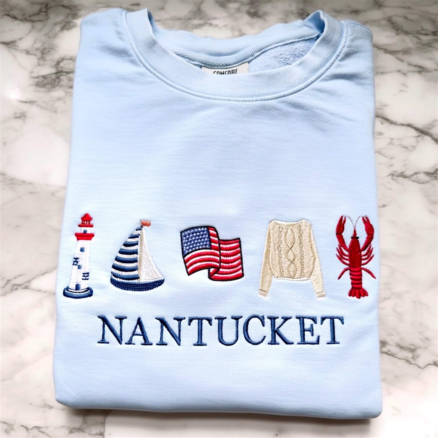 Personalized Comfort Colors coastal embroidered lightweight sweatshirt in the color Hydrangea featuring a full seaside icon design with a custom location.