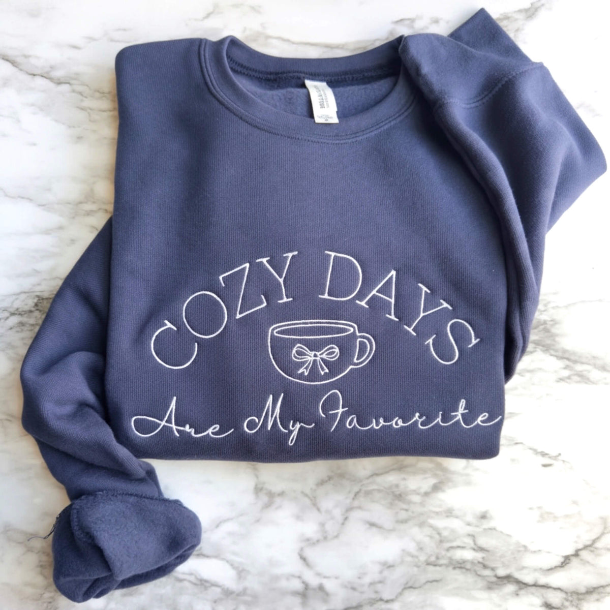 Navy Bella + Canvas crewneck sweatshirt with white Cozy Days Are My Favorite embroidered design featuring a coffee cup and bow.