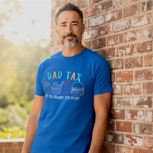 Gildan Royal Blue T-shirt embroidered with a design that says Dad Tax across the top and then four different food outline shapes underneath, with the tag line that says If I'm Buyin' I'm tryin' on a male model.