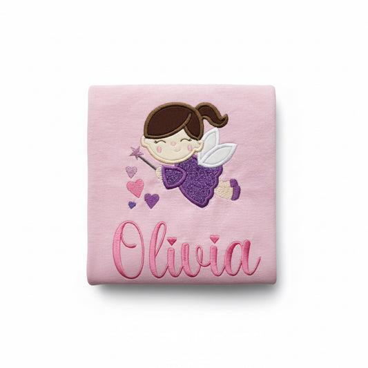 Gildan Light Pink T-Shirt with the cutest fairy embroidered design.  The fairy is dressed in a purple glittery dress holding a magic wand with hearts in the colors pink and purple cascading down.  You can personalize the shirt by adding your child's name in the color pink.  Font used will be dependent on the length of the name.