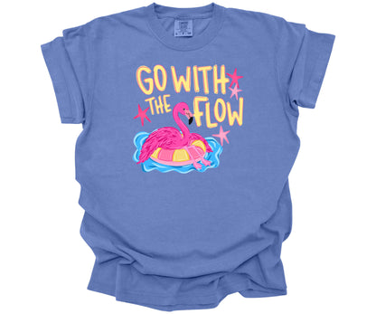 Comfort Colors T-Shirt in the color Mystic Blue with a cute design that shows a hot pink flamingo hanging out on a pool floaty with the words "Go with the Flow" across the top.  Perfect for summer.