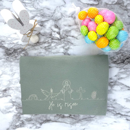 Gildan Softstyle Midweight T-Shirt in the color Sage with Christian symbolic line art and the words "He is risen" - all embroidered in a beige thread that creates a subtle look.