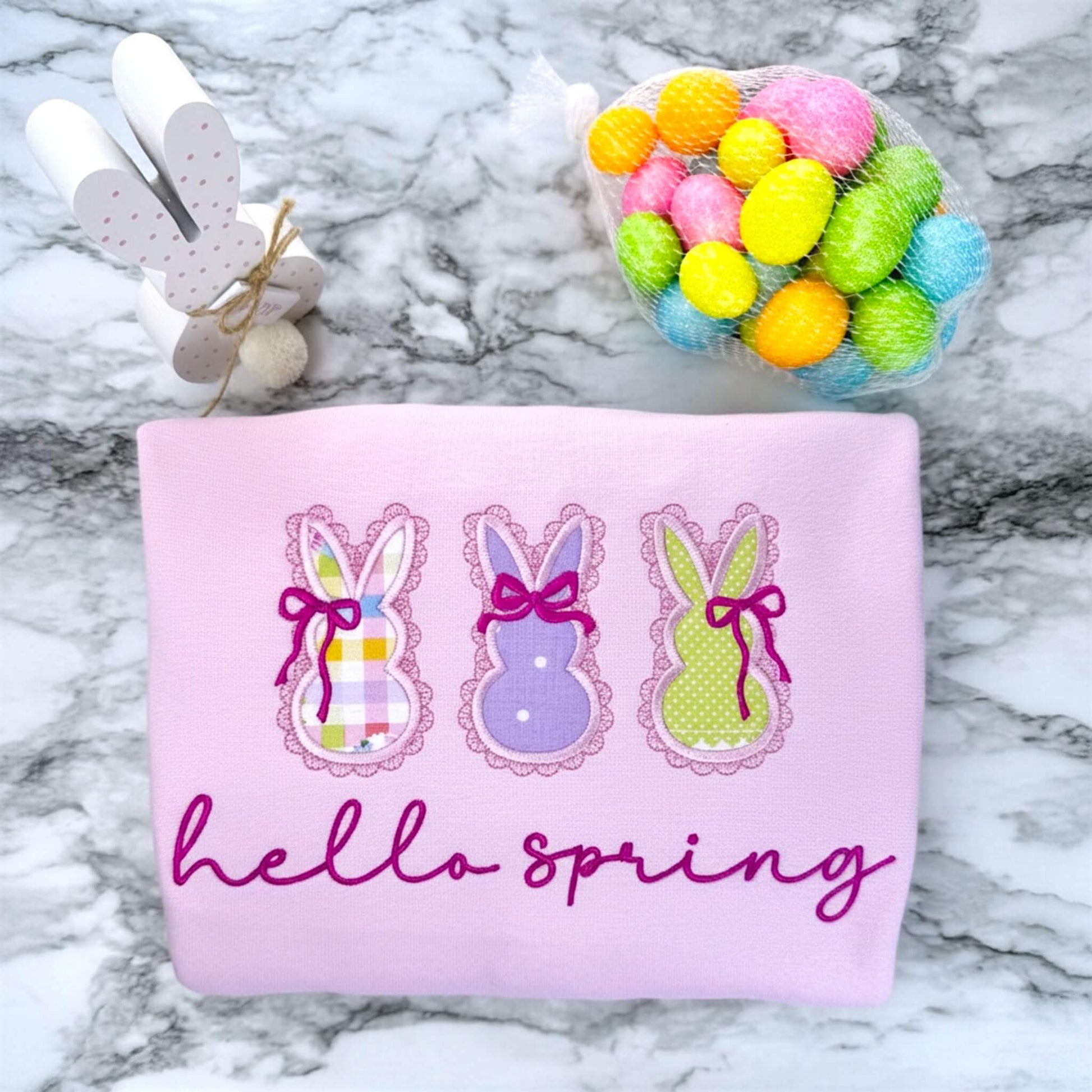 Embroidered Gildan Softstyle Pink Sweatshirt with 3 applique bunnies featuring spring fabric colors, cute coquette bows and the words "hello spring" in a script font.