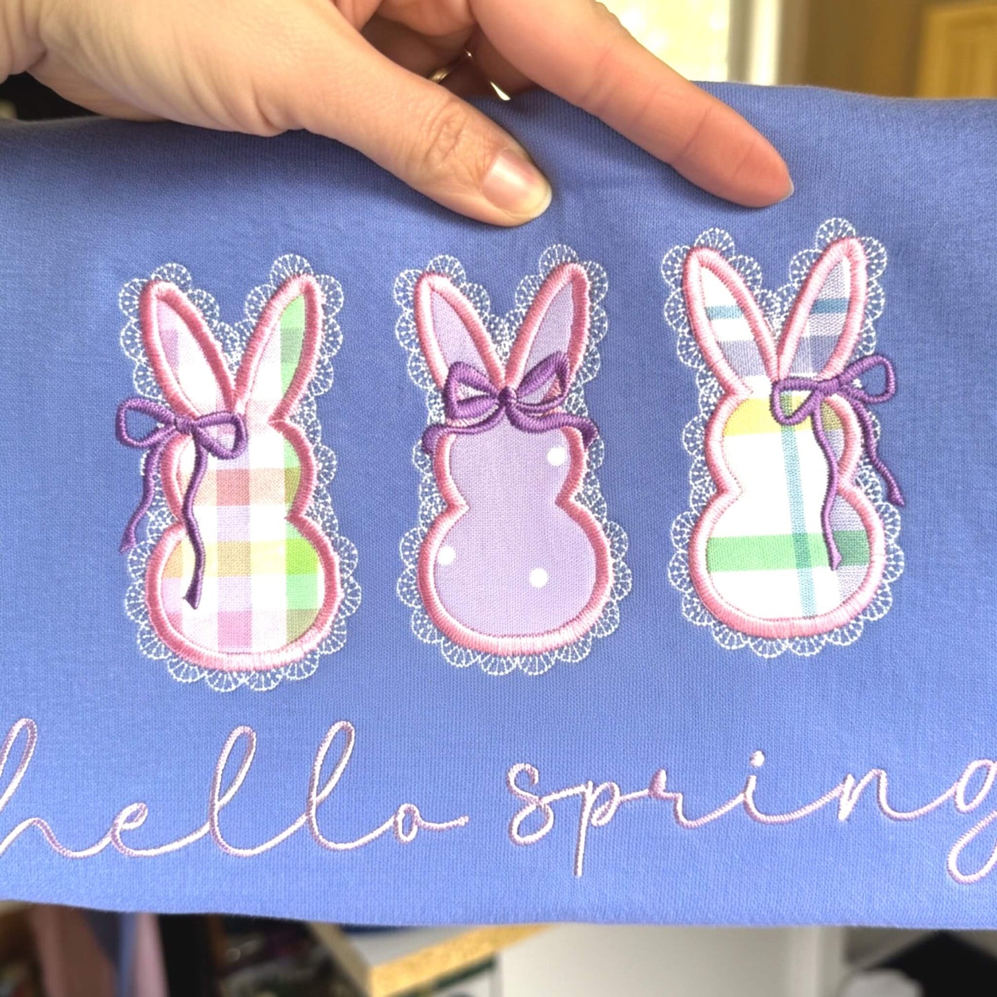 Embroidered Gildan T-Shirt in the color Violet with 3 applique bunnies featuring spring fabric colors, cute coquette bows, delicate lace border and the words "hello spring" in a script font.