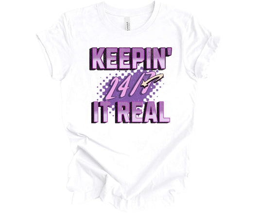 Bella Canvas T-shirt in White with the words Keepin' It Real 24/7 in different shades of purple with a 3D effect