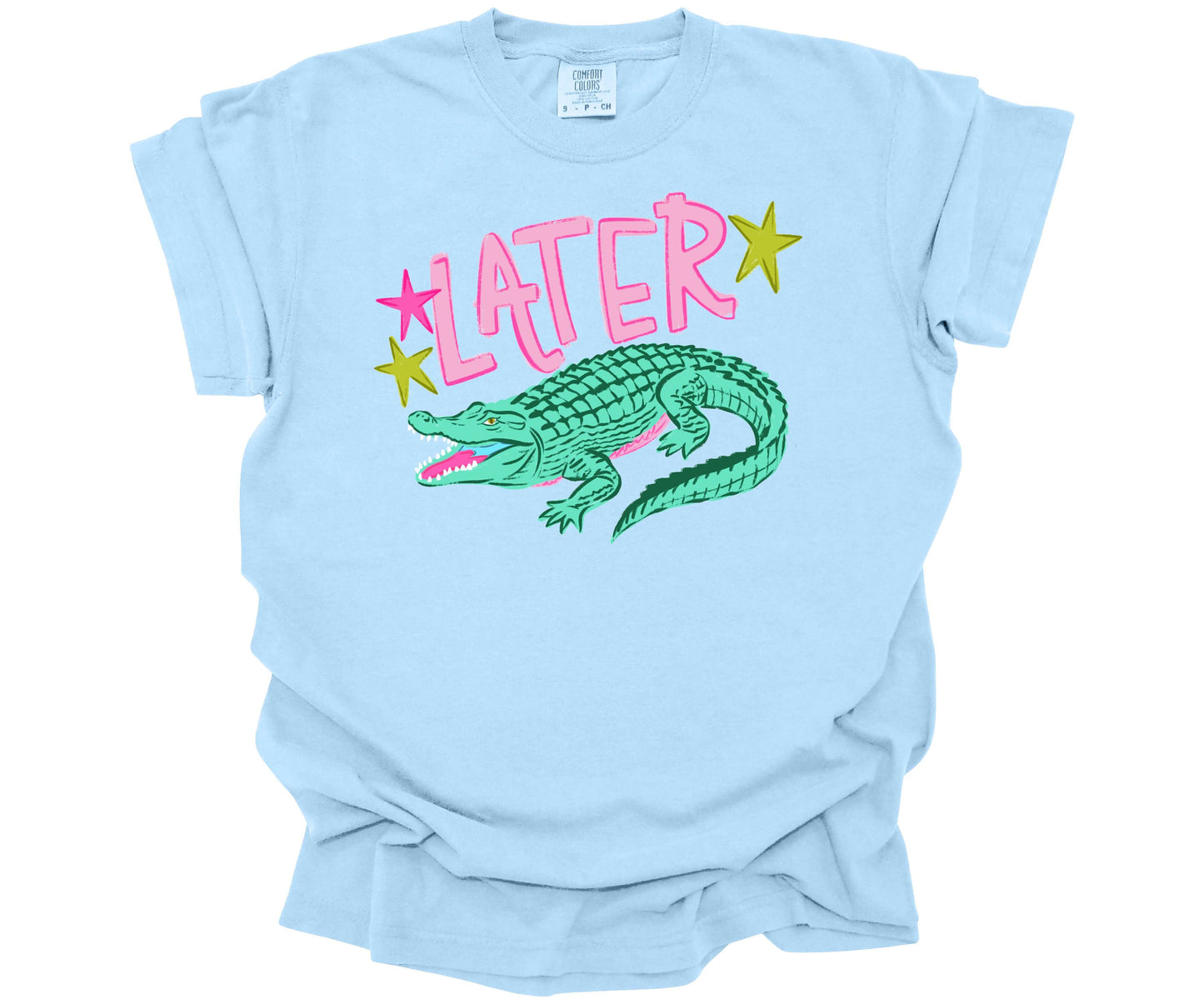 Comfort Colors Tee in the color Hydrangea (light blue) with a cute nostalgic graphic that is reminiscent of the saying: "See ya later alligator".  The design has the word Later surrounded with stars and an alligator underneath.