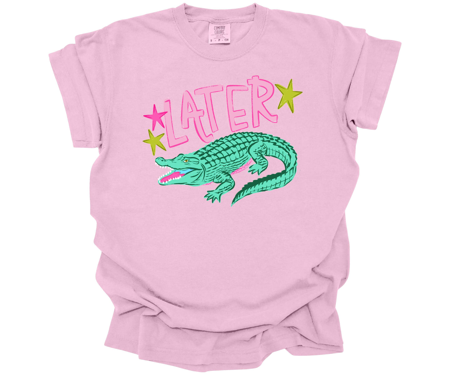 Comfort Colors Tee in the color Blossom (light pink) with a cute nostalgic graphic that is reminiscent of the saying: "See ya later alligator".  The design has the word Later surrounded with stars and an alligator underneath.