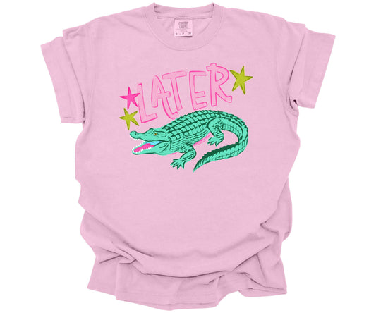 Comfort Colors Tee in the color Blossom (light pink) with a cute nostalgic graphic that is reminiscent of the saying: "See ya later alligator".  The design has the word Later surrounded with stars and an alligator underneath.