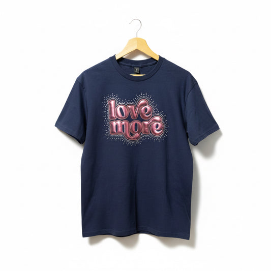 Your choice of a Bella Canvas or Gildan Softstyle Navy T-Shirt with a Love More design that is made up of Puff HTV (which gives it a 3D look) in a rose pink color that is outlined in rose gold glitter. There is a splatter of Crystal AB rhinestones surrounding the entire design.