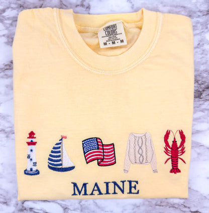 Embroidered Comfort Colors t-shirt in the color butter featuring a coastal-inspired design with a personalized custom beach destination text that can be changed to your favorite location.  Part of the Coastal Collection.