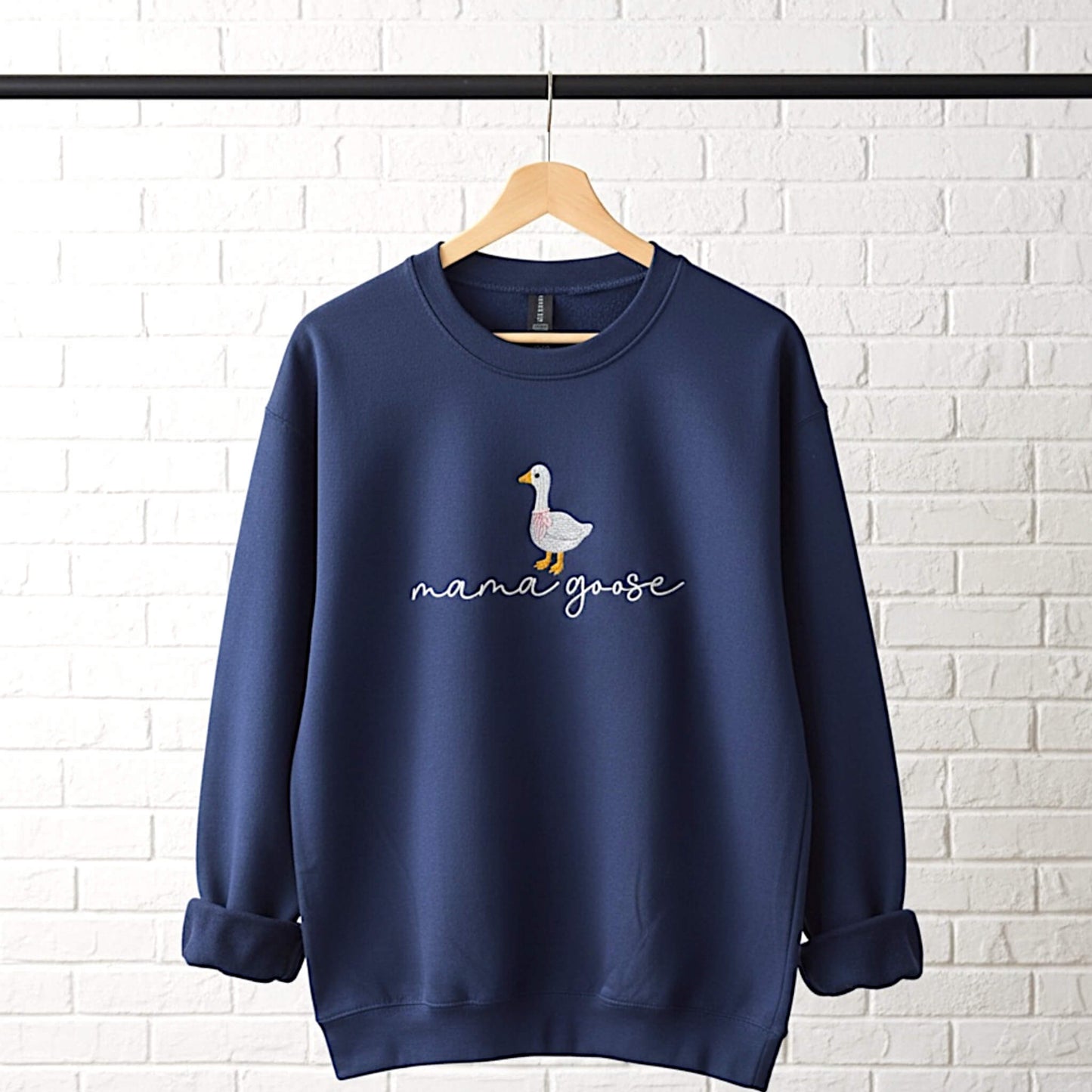 Gildan Softstyle Navy Sweatshirt with an embroiderered design of a cute goose with a pink bow around its neck and the words "mama goose" in a script font.