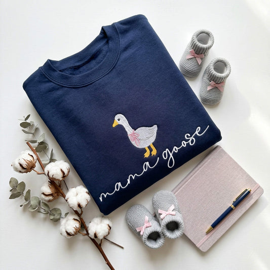 Gildan Softstyle Navy Sweatshirt with an embroiderered design of a cute goose with a pink bow around its neck and the words "mama goose" in a script font.