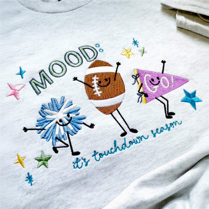 Detailed close-up of colorful Mood: Its Touchdown Season embroidered design with cute football characters, and colorful stars.
