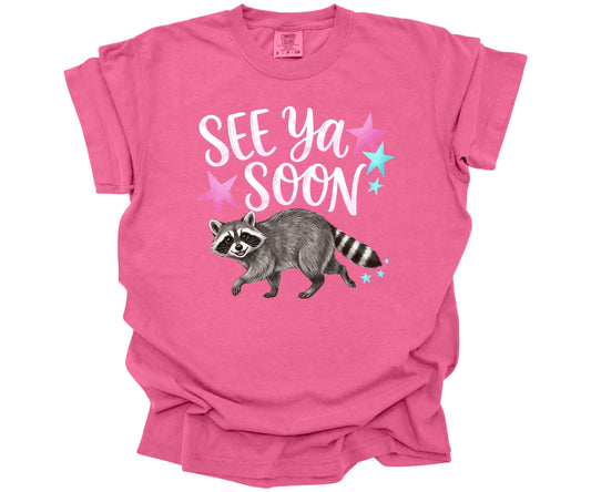 Comfort Colors Tee in the color Crunchberry with a cute funny design.  The design says "See Ya Soon" with a Raccoon underneath the words.