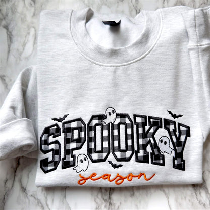 Spooky Season Halloween embroidered design on a Gildan softstyle Ash Gray sweatshirt with checkerboard appliqué, orange script lettering, and cute ghosts and bats.