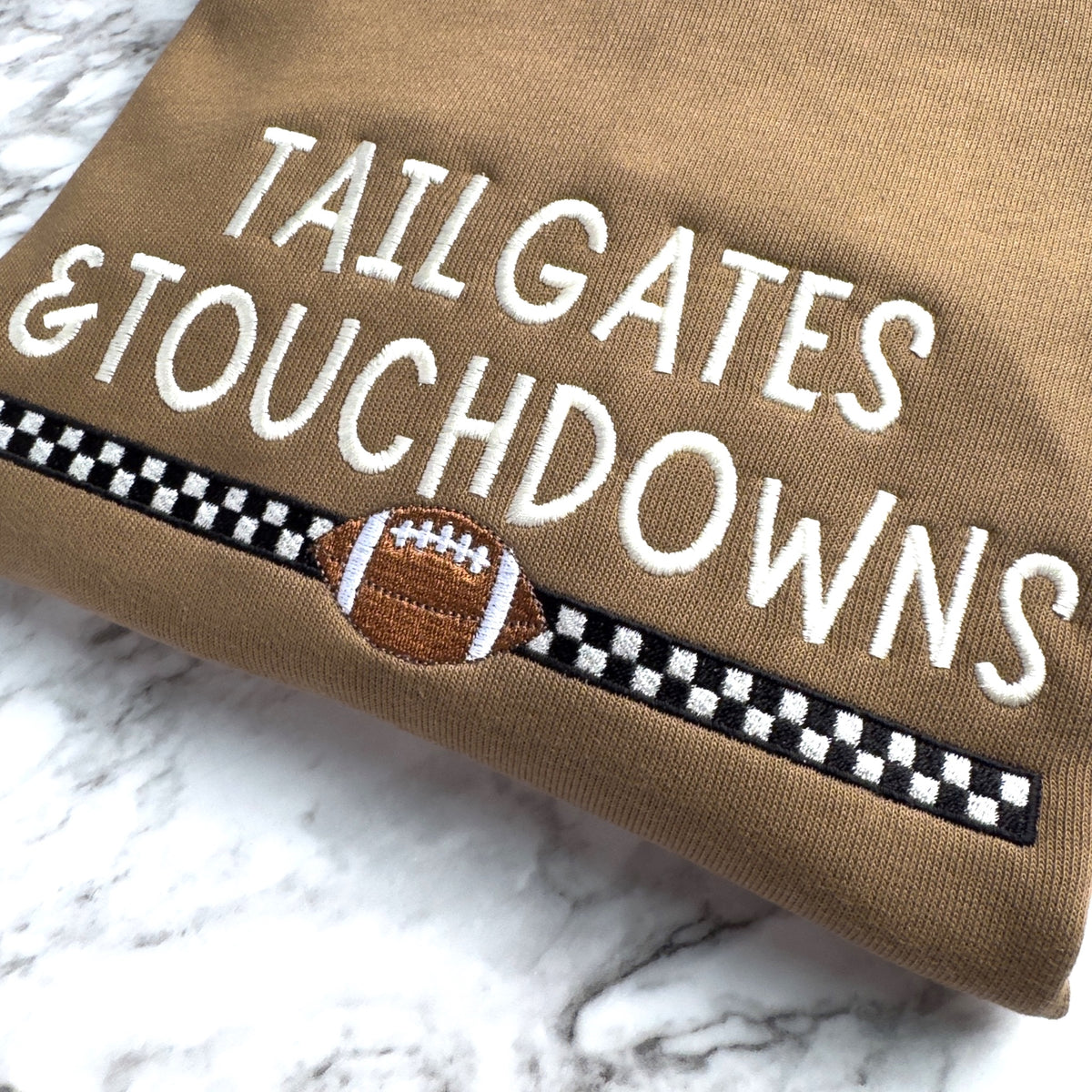 Close up of embroidered Bella Canvas 3945 football sweatshirt in Vintage Brown with Tailgates & Touchdowns design with racing stripe and football underneath.