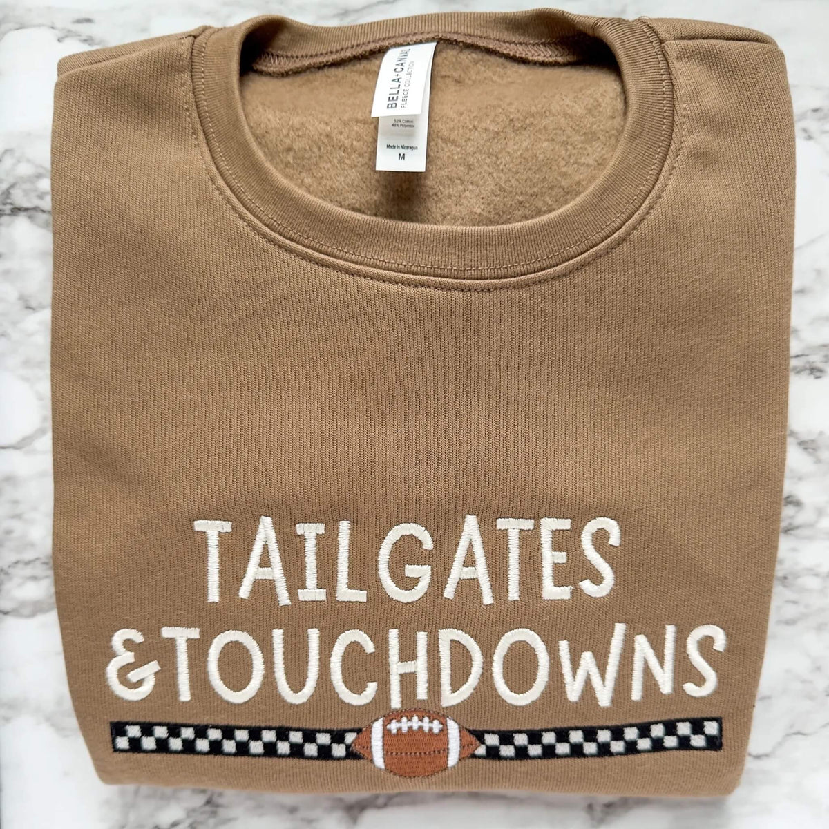 Embroidered Bella Canvas 3945 football sweatshirt in Vintage Brown with Tailgates & Touchdowns design with racing stripe and football underneath.
