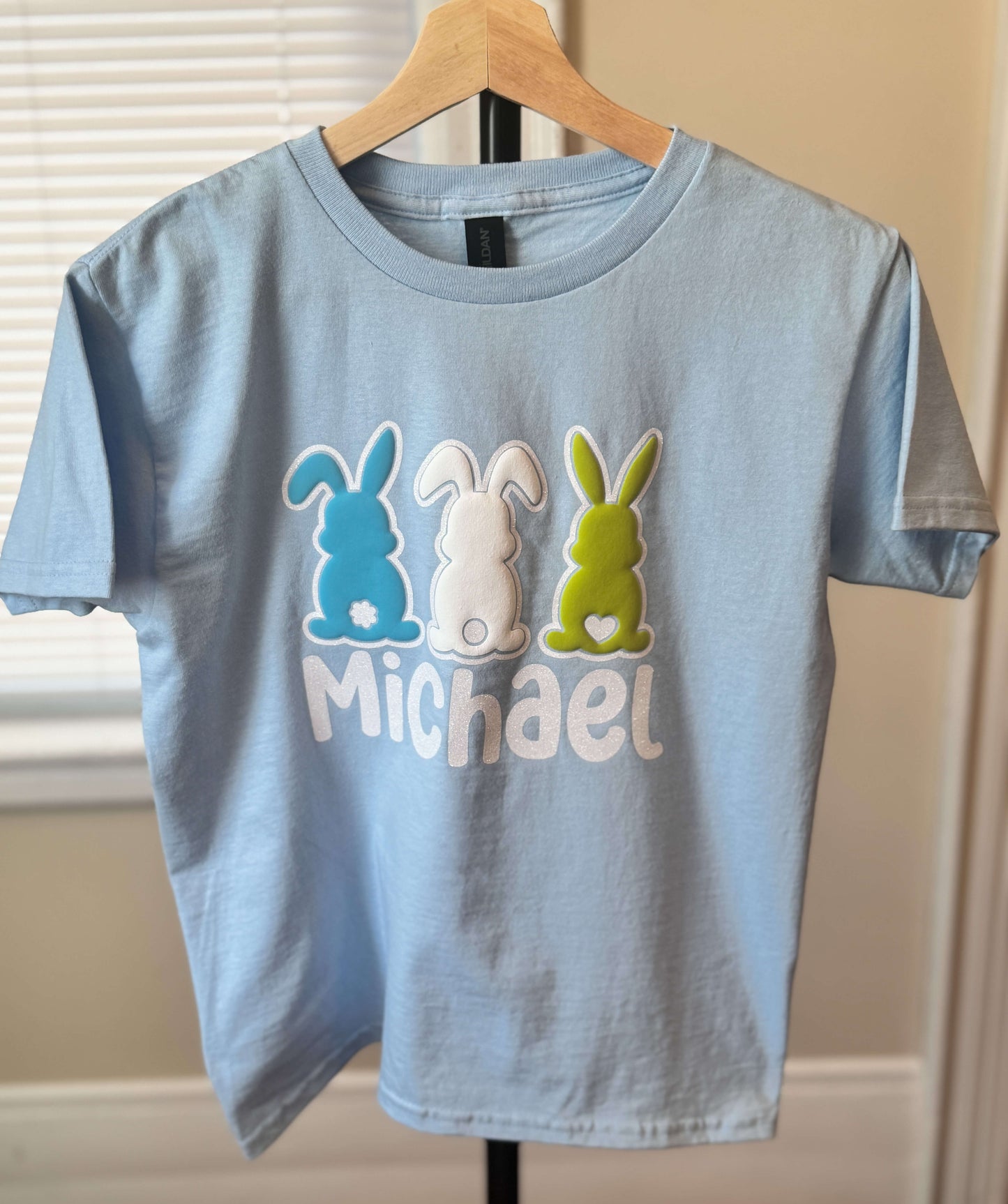 Gildan Youth Light Blue Easter T-Shirt with three bunnies in 3D Puff HTV - each in a different color outlined in glitter HTV which can be personalized with your child's name.