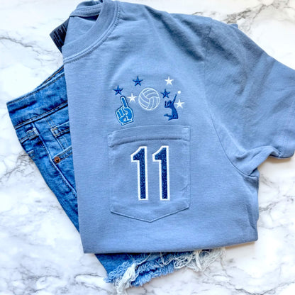 Personalized Comfort Colors Blue Jean volleyball pocket tee with embroidered volleyball design, custom jersey number in blue glitter HTV, and permanently closed pocket.